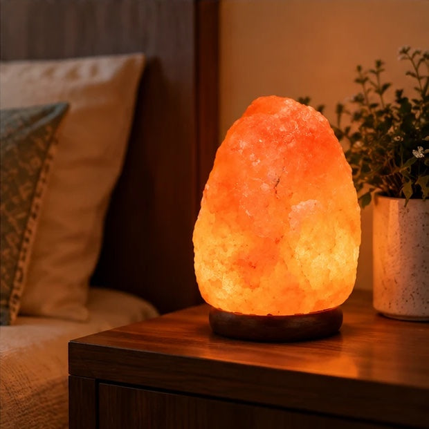 Salt lamp on a bedside table glowing softly beside the bed