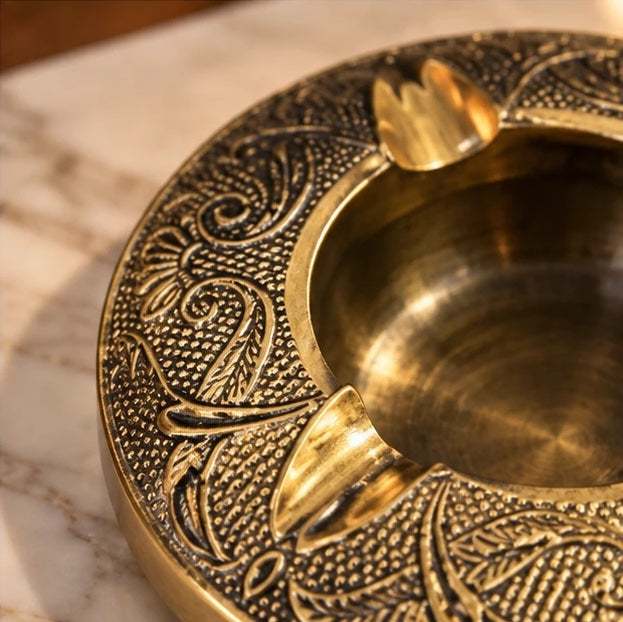 Close-up of the brass ashtray's embossed rim, rests and polished bowl