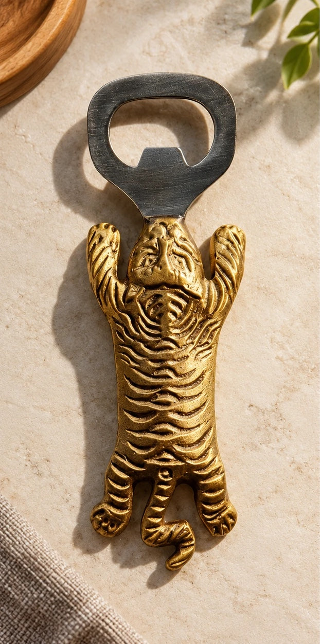 Top view of the brass tiger bottle opener on cream marble, showing the striped detailing